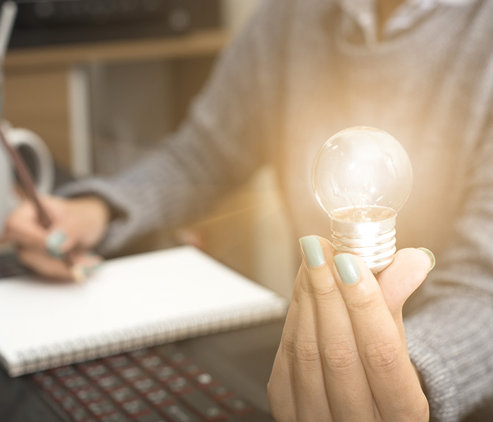 taking notes and holding a lightbulb